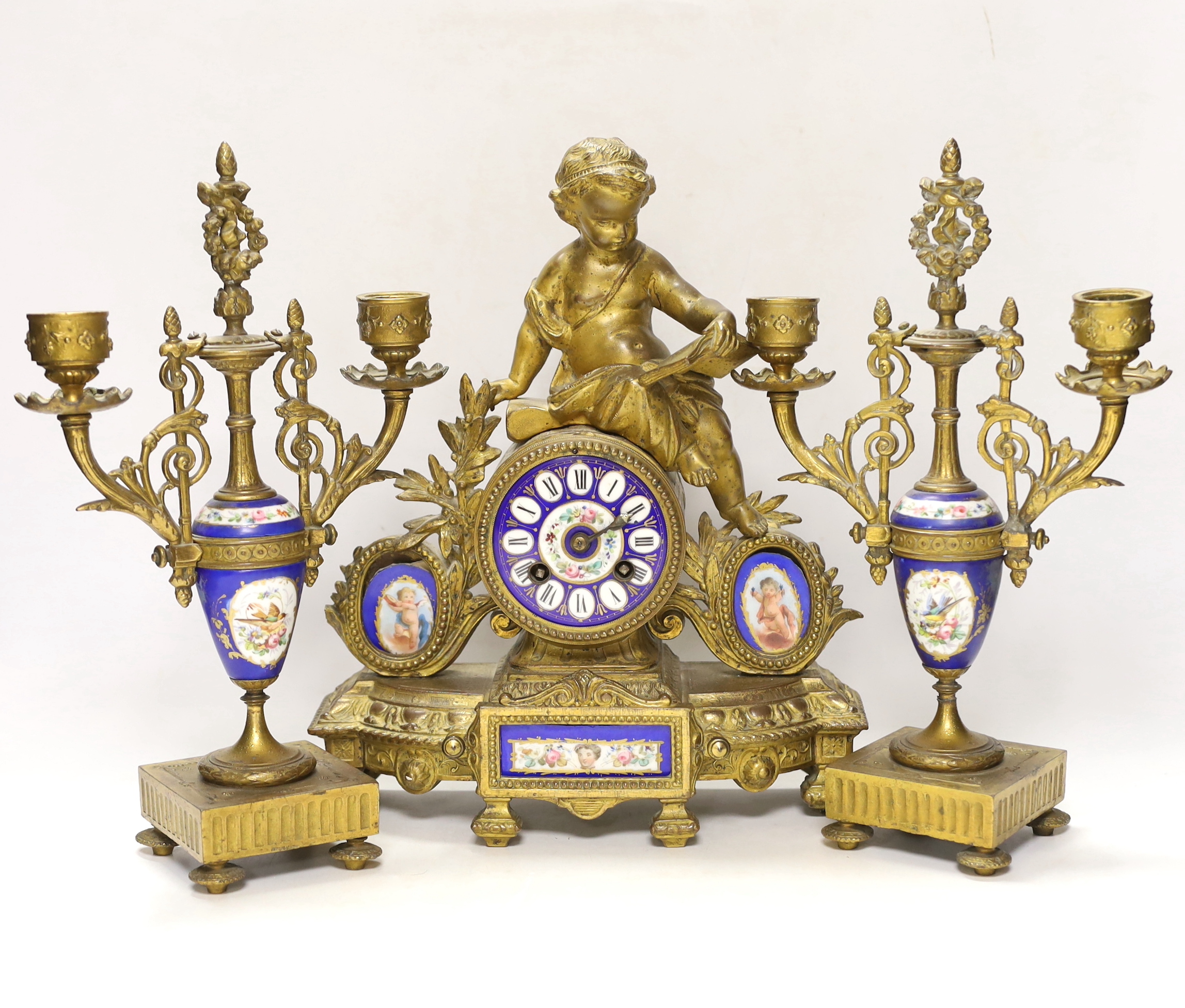 A 19th century ornate French gilt brass and porcelain clock, with two matching two branch candelabra garnitures, clock 31cm high
